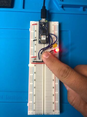 Circuit with Arduino 33, on breadboard, a number of connections, one red LED, one yellow LED, and a blue push button.